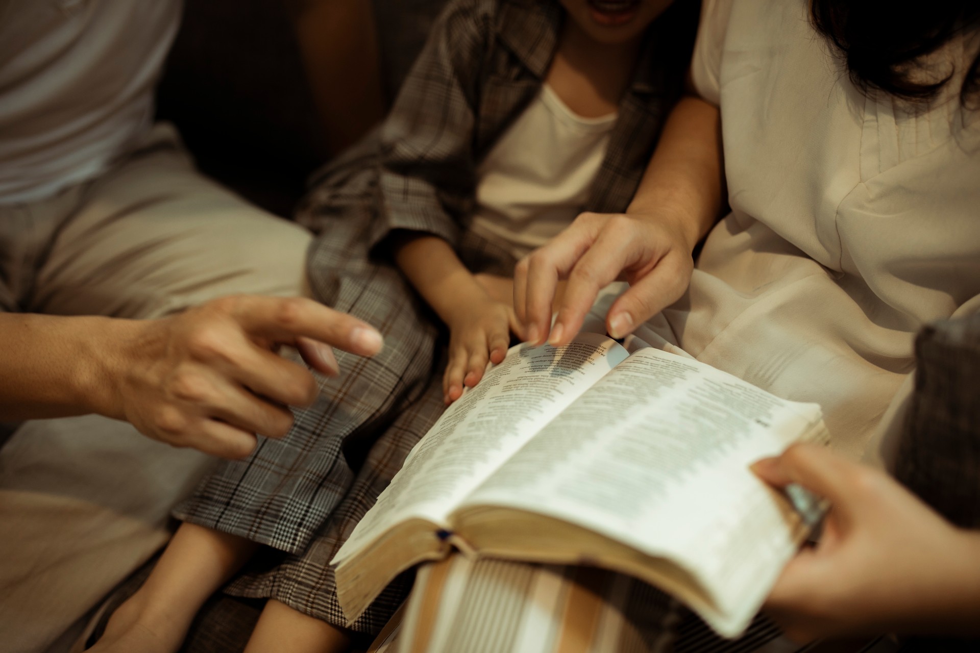 asian family praying and reading bible together at home